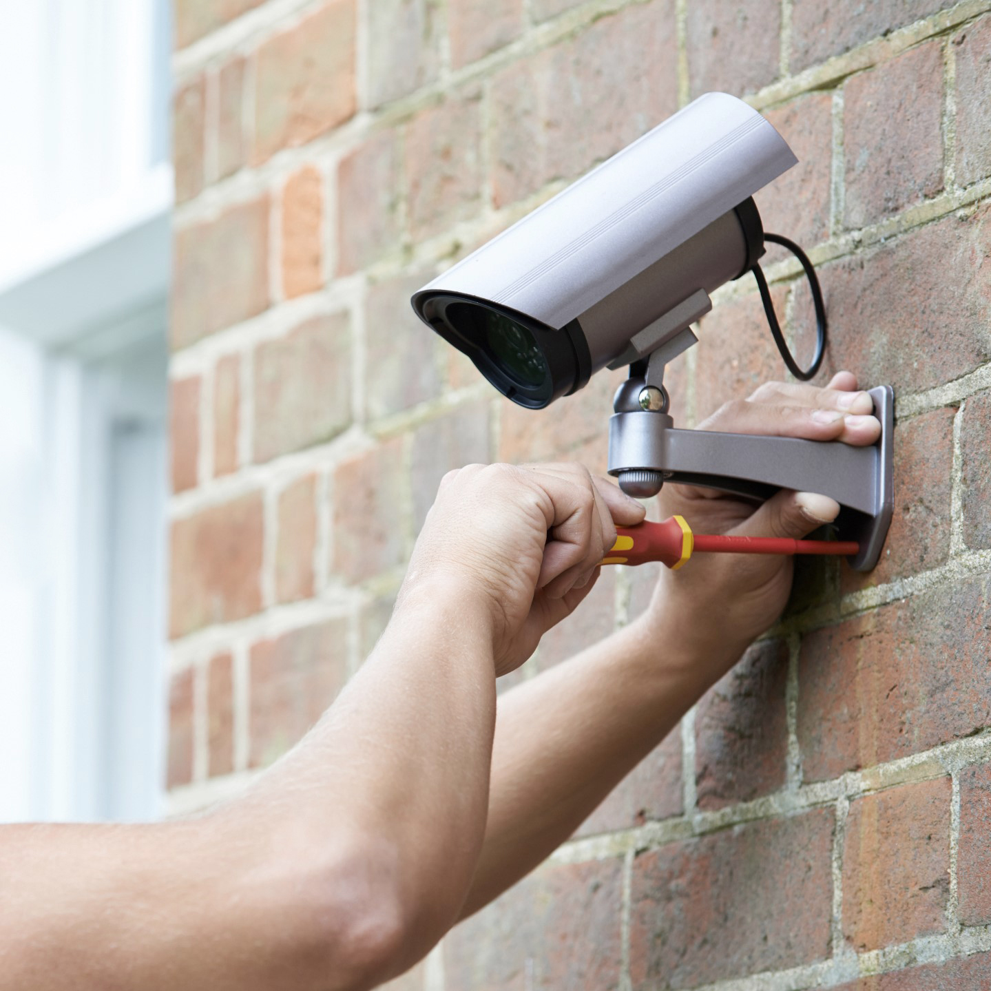 Security Consultant Fitting Security Camera To House Wall